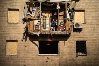 A man stands on a damaged balcony following a Russian drone strike in Kharkiv